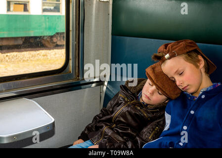 two boys sleeping in a train during their travel Stock Photo