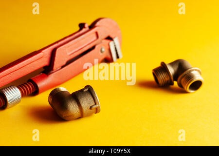 A monkey wrench on the yellow background with some fitting connectors. for design and decoration. Stock Photo
