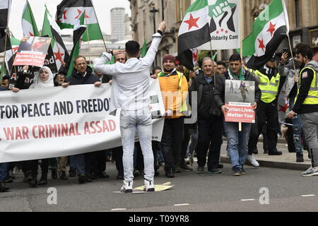 London, Greater London, UK. 16th Mar, 2019. A man seen waving before the protesters holding a banner and flags during the 8th Anniversary of the Syrian Revolution protest.Syrians marched from Paddington Green to Whitehall to demand for a peaceful solution of the war in Syria and restore democracy, they also call for an end of forced displacement, war crimes and foreign occupation in the country. Credit: Andres Pantoja/SOPA Images/ZUMA Wire/Alamy Live News Stock Photo