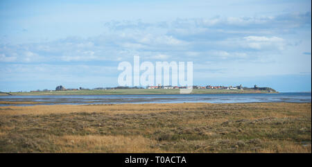 The Island of Lindisfarne from The Mainland with Bamborough castle in the distance Stock Photo