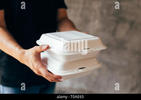 Close-up of delivery man handing a slack of foam lunch box - Foam box is toxic plastic waste. Used for recycling and environment saving concept Stock Photo