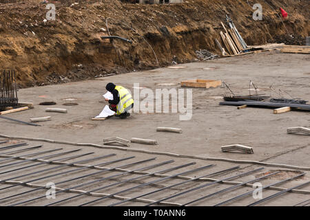 construction worker studying a engineering plan in the foundation of a new building Stock Photo