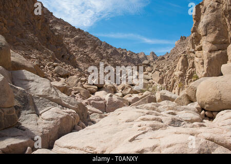 Rocky mountain slope landscape in a remote arid desert environment with blue sky background Stock Photo