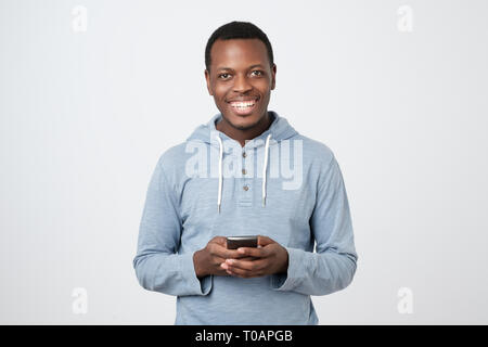 African young man using mobile phone chatting in internet with her friends. Stock Photo