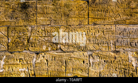 Wall with limestone bricks with illegible engravings that have been written by people with the passage of time Stock Photo
