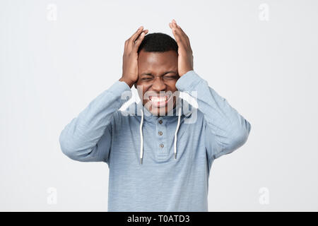 African american man feeling severe headache. He is suffering, holding his head with both hands Stock Photo
