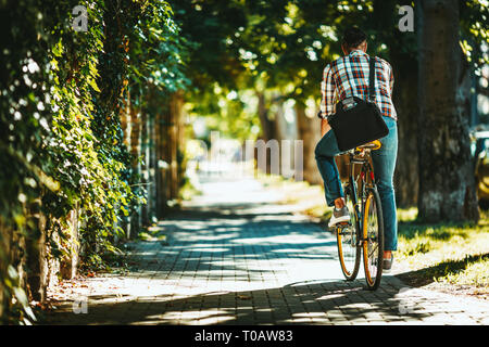 A handsome young man goes to the city with his bike. He is riding the bike, happy because of nice weather and peaceful street. Stock Photo
