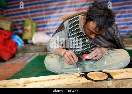 Tibetan man painting wooden board with traditional patterns Stock Photo