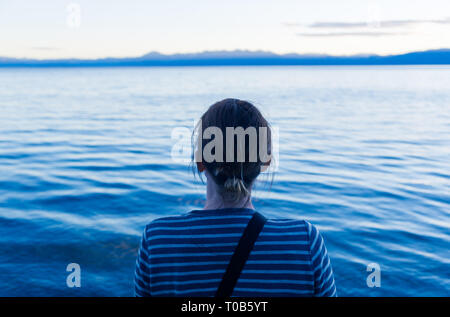 A middle-aged woman sitting and thinking by the water Stock Photo