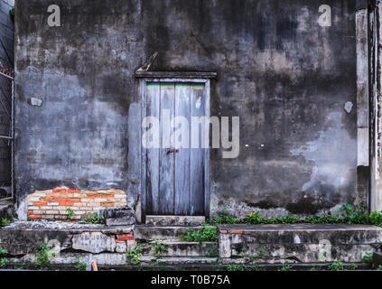 Vintage retro Home interior architectural design, plain old aged tropical weathered textured faded color wood panel board door and moldy wall of tradi Stock Photo