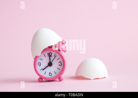 Egg shells and small alarm clock on pastel pink background minimal easter time creative concept. Space for copy. Stock Photo