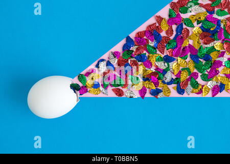 Egg shell with colorful leaves on blue background minimal easter and spring creative concept. Stock Photo