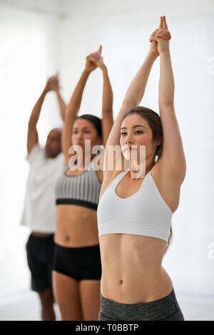 Young woman concentrates on her pose as she attends a yoga class. Stock Photo