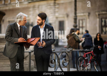 Mature businessman has a chance meeting with a young colleague while they are out in the city. Stock Photo