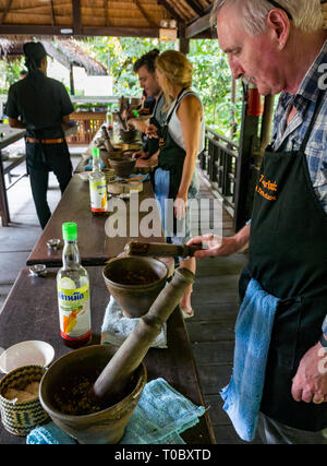 Tourists in SE Asian Lao cooking lesson using pestle and mortar and fish sauce, Tamarind cookery school, Luang Prabang, Laos Stock Photo