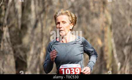 ALMATY, KAZAKHSTAN - March 16, 2019: portrait of a beautiful old woman who runs through the woods during the spring marathon in the city of Almaty, in Stock Photo