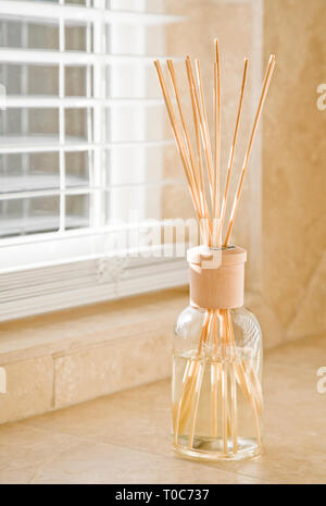 Sunlight shining through window blinds and fragrance diffuser on stone tile bathroom counter. Clean, bright, fresh house home interior decor elements. Stock Photo