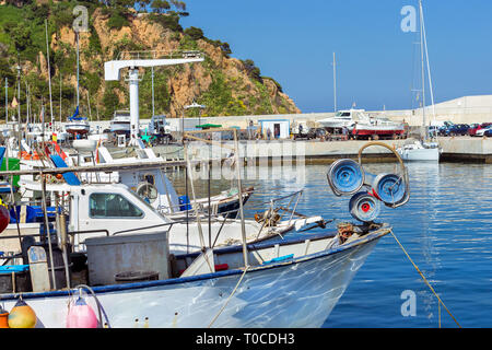 Fishing boats and private yachts moored at pier in seaport Blanes. Vessels with catch of sea fish delicacies. Sailing and motor boats are moored at co Stock Photo