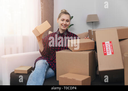 woman sit on couch at home with lot of cardboard boxes Stock Photo