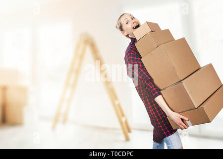 woman moving into new apartment holding stack of cardboard boxes Stock Photo