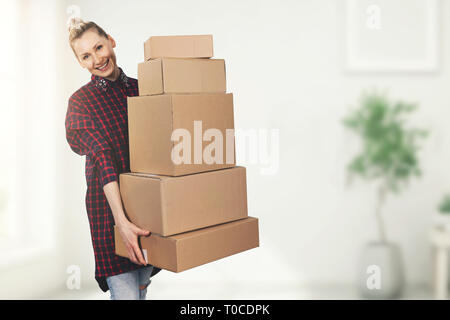 happy woman standing in new house with boxes in hands Stock Photo