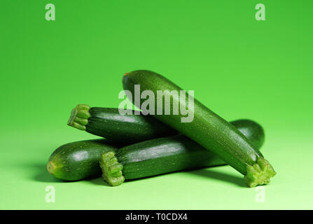 Zucchini vegetables portrait concept with four fresh organic baby zucchini close up view on green background with copy space. Stock Photo