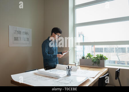 Businessman standing and looking blueprint at office meeting room Stock Photo