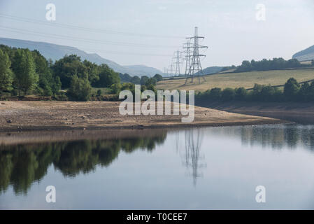 Sunny summer morning at Bottom's reservoir in the Longdendale valley, Derbyshire, England. Pylons reflected in the water. Stock Photo