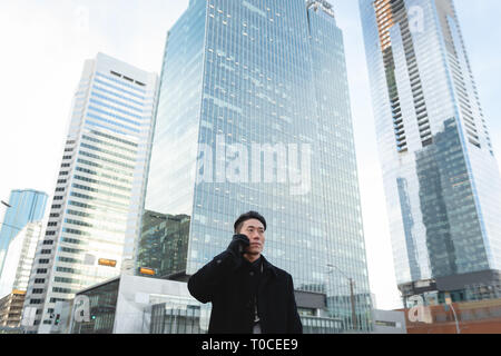 Young Asian businessman  talking on mobile phone while standing on street Stock Photo