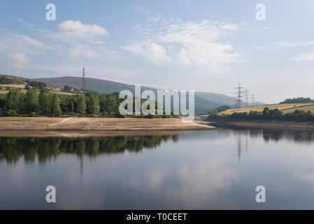 Sunny summer morning at Bottom's reservoir in the Longdendale valley, Derbyshire, England. Pylons reflected in the water. Stock Photo