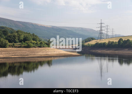 Sunny summer morning at Bottom's reservoir in the Longdendale valley, Derbyshire, England. Pylons reflected in the water. Stock Photo