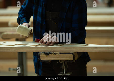 Carpenter using chisel with hammer in workshop Stock Photo