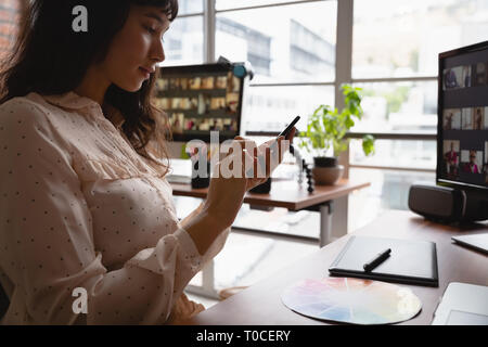 Businesswoman using smart phone in office Stock Photo