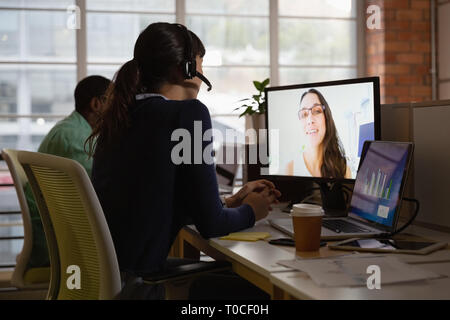 Businesswoman making video call to business partner in office at desk Stock Photo