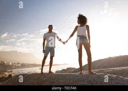 Couple holding hands and standing on rock near sea side Stock Photo