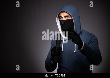 Young gangster in hood on grey background Stock Photo