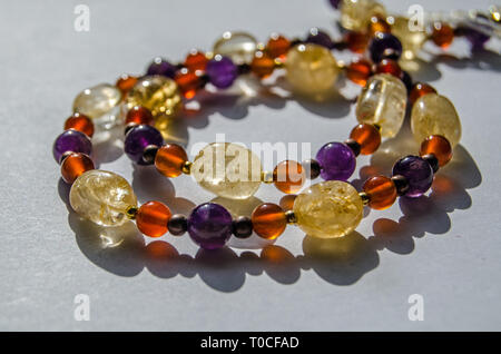 Bracelet and necklace hand made using colourful semi-precious gemstone beads including yellow citrine, purple amethyst and orange carnelian. Stock Photo