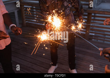 Group of friends enjoying out with sparklers in balcony Stock Photo