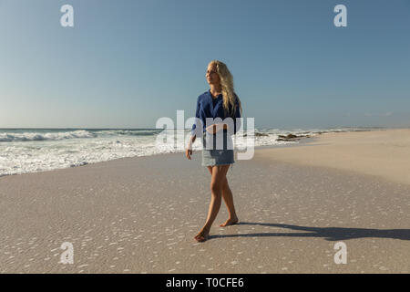 Beautiful blonde Caucasian woman walking at beach on a sunny day Stock Photo