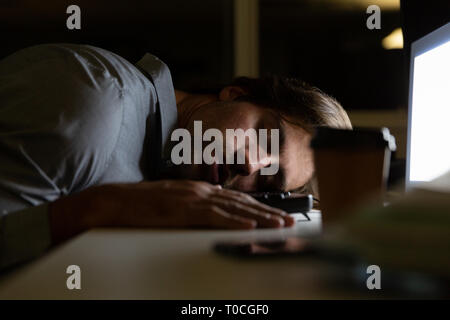 Young Caucasian male executive sleeping at desk in a modern office Stock Photo