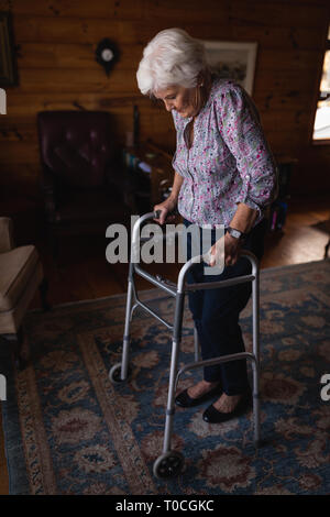 Active senior woman walking with walker in living room at home Stock Photo