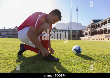 Male rugby player tying shoelaces on the rugby ground Stock Photo