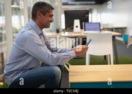Businessman using mobile phone at desk in office Stock Photo