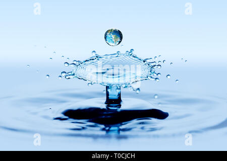 Water splatter and splash. Collision effect of two falling rain drops. Earth image visible in drop. Stock Photo