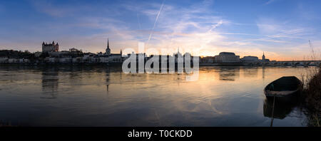 Panorama view of Saumur town from across the Loire river at sunset, with the medieval castle and the old town with Saint-Pierre church. Stock Photo