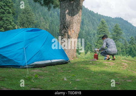 A person switching on the gas to cook food near his camping tent at a camping site in Pahalgam in Kashmir Stock Photo