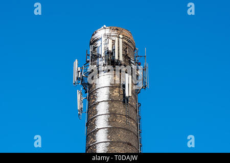 Telecommunication antennas on chimney covered by snow in cold winter and clear sky Stock Photo