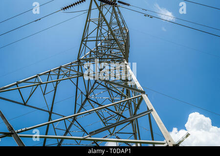 Low angle shot of a power transmission tower against blue sky with some low clouds in Kashmir, India Stock Photo