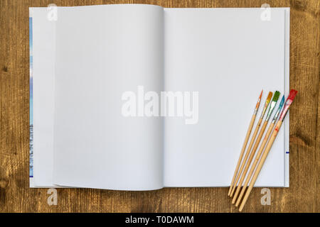 White blank pages sketchbook with paintbrushes on wood table Stock Photo