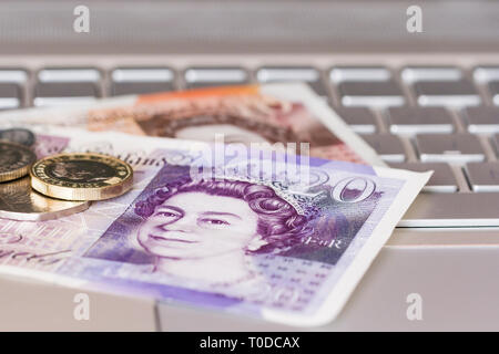 English sterling money on a laptop keyboard. Online banking, online shopping concepts. United Kingdom Stock Photo